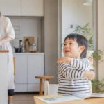 朝の家事のそばで幼児が英語の歌に合わせて楽しく動く家庭の場面