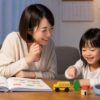 幼児が英語レッスン後に母親と家で絵本やおもちゃを使って復習する場面