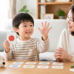 幼児が母親と短い英語フレーズをまねして手をふる明るい家庭の場面