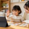 幼児が家庭でオンライン英語レッスンを楽しみ母親がそばで見守る明るい場面