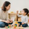 2歳の子どもがブロック遊びをしながら親と楽しく言葉を交わす場面