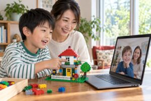 親の見守りのもとで自作のブロックの家を画面越しの友達へ紹介する小学生のイメージ