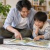 音声を参考に親子で絵本を楽しむ父親と小学生のイメージ