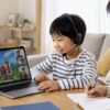 小学生がヘッドセットを使ってゲーム英語を楽しみながら母親が見守る場面