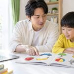 父親と子どもがパソコンのそばで絵本の絵を指さすイメージ（AI生成）