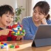 母親と子どもが手作りのブロックの家を画面に見せるイメージ（AI生成）