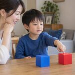 母親の隣で二つの積み木から赤を指さして選ぶ子どものイメージ（AI生成）