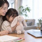 母親と幼児がぬいぐるみをオンラインの先生に見せるイメージ（AI生成）