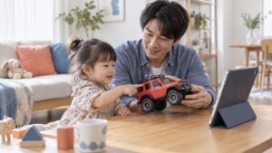 父親と幼児が大きなおもちゃの車を画面に見せるイメージ（AI生成）