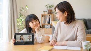 QQキッズに少し飽きた小学生と母親が家庭で英語を遊びに戻す方法を考えている場面