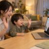 仕事帰りの母親と幼児が一緒に画面の先生へ手を振る家庭のイメージ